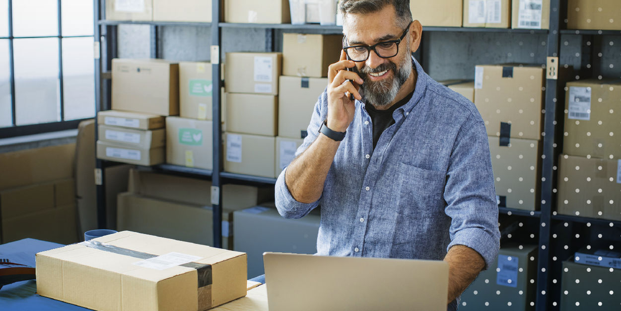 Small business owner surrounded by boxes with laptop and phone