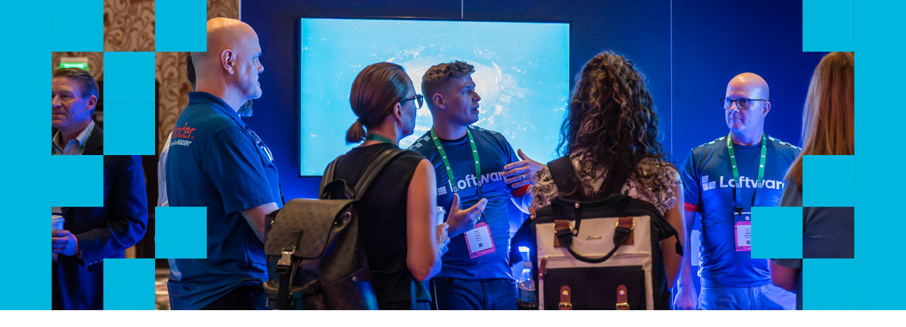 Conference attendees at exhibit booth engaged with exhibitor