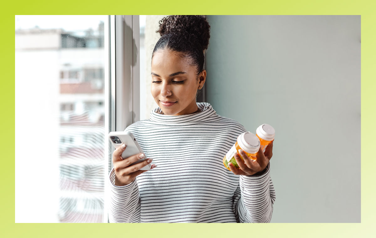 person holding medication looking up information on phone