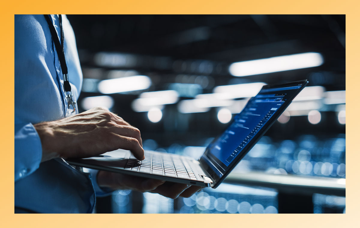 person typing on laptop in server room