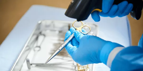 Hands wearing gloves scanning medical instrument