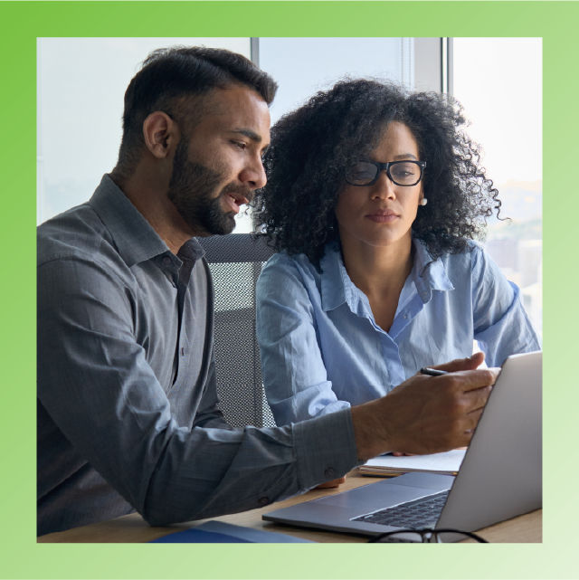 photo of two business people working on a laptop