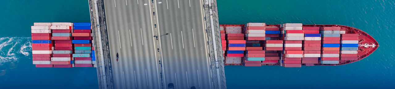 photo of cargo ship crossing under bridge