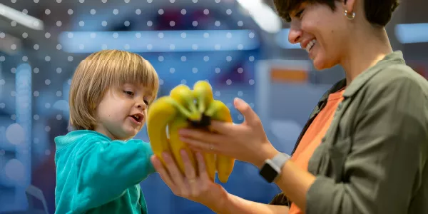 Woman with child in grocery store holding bananas 